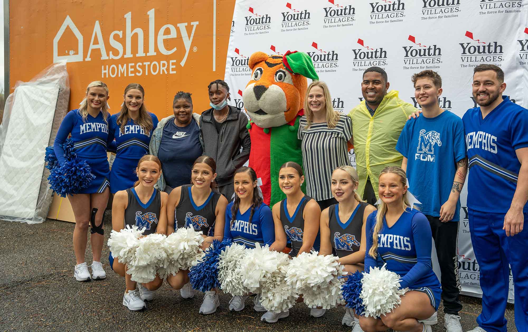 Youth Villages staff, University of Memphis Cheer team, and Intercept family in front of Ashley Home Furniture truck