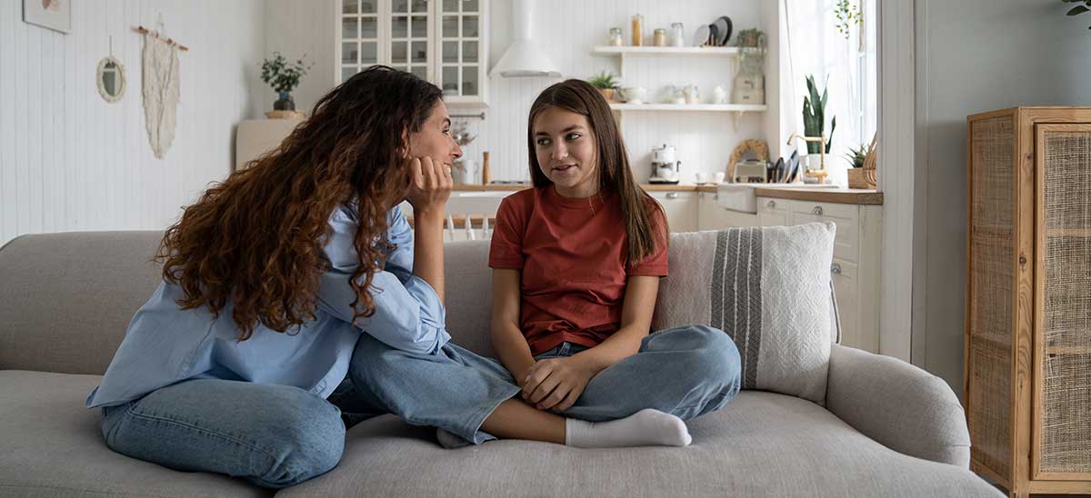 Mom and daughter sitting on couch smiling at each other
