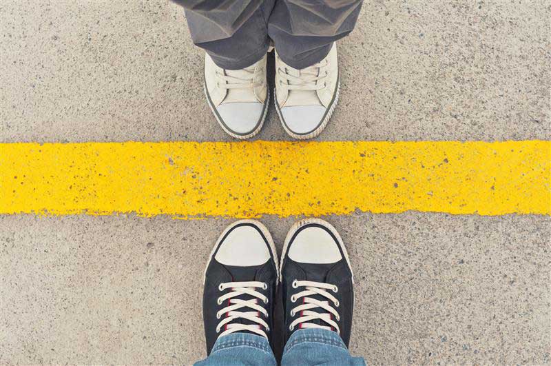 photo of two pairs of shoes on each side of a yellow line facing each other