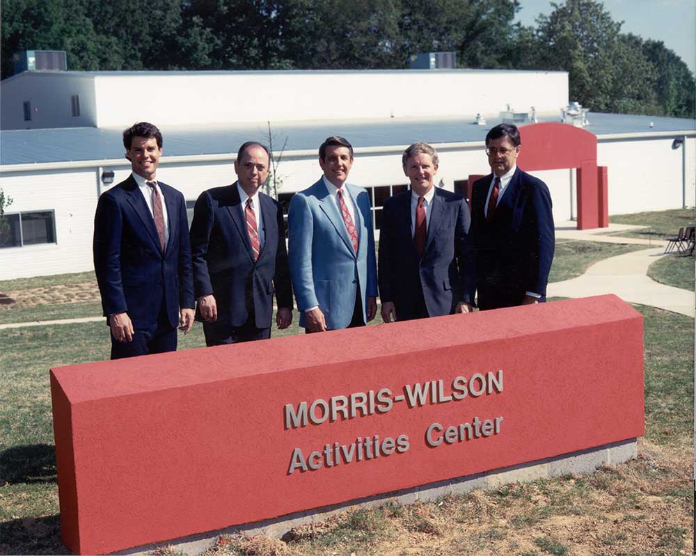 Pat Lawler, Spence Wilson and other supporters behind Morris-Wilson Activities Center sign
