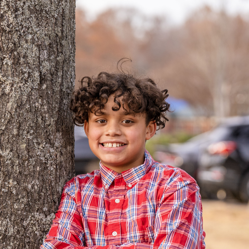 Elijah standing next to a tree smiling