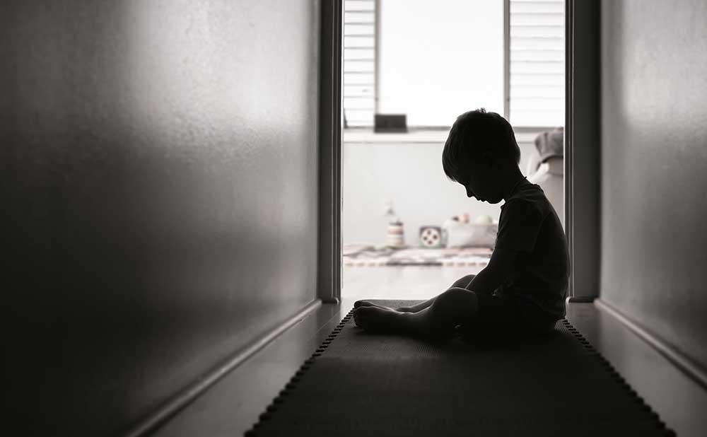 young child sitting in a dark hallway