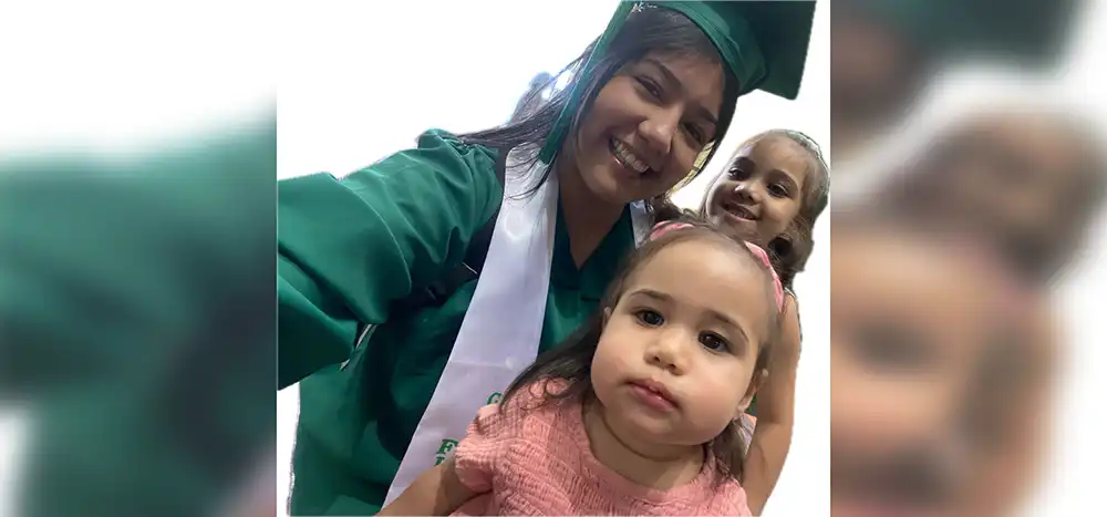 LifeSet Scholar, Sabina, in her graduation cap and gown with her two kids
