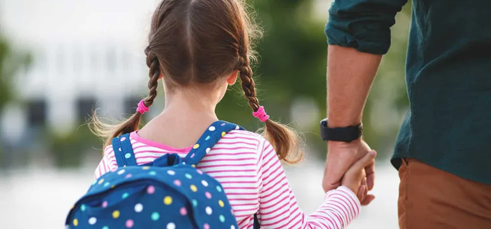 daughter carrying backpack holding dad's hand